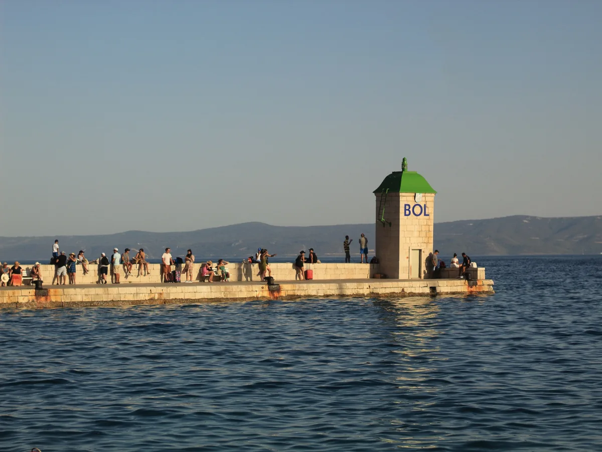 Turisti čakajúci na transport v Bole na Brači