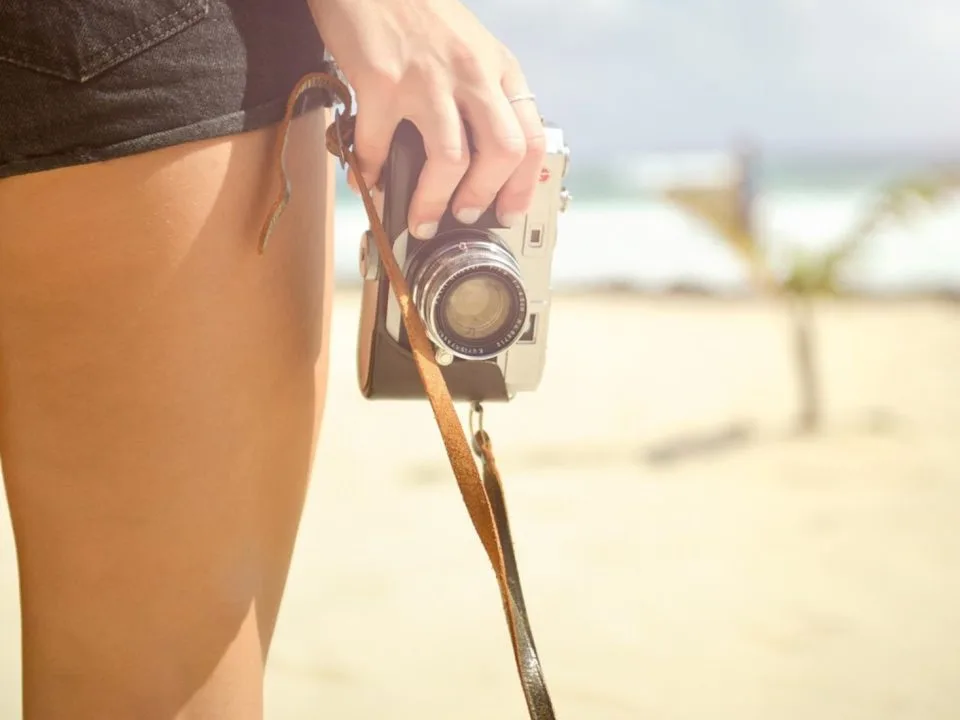 Girl holding a vintage camera at the beach