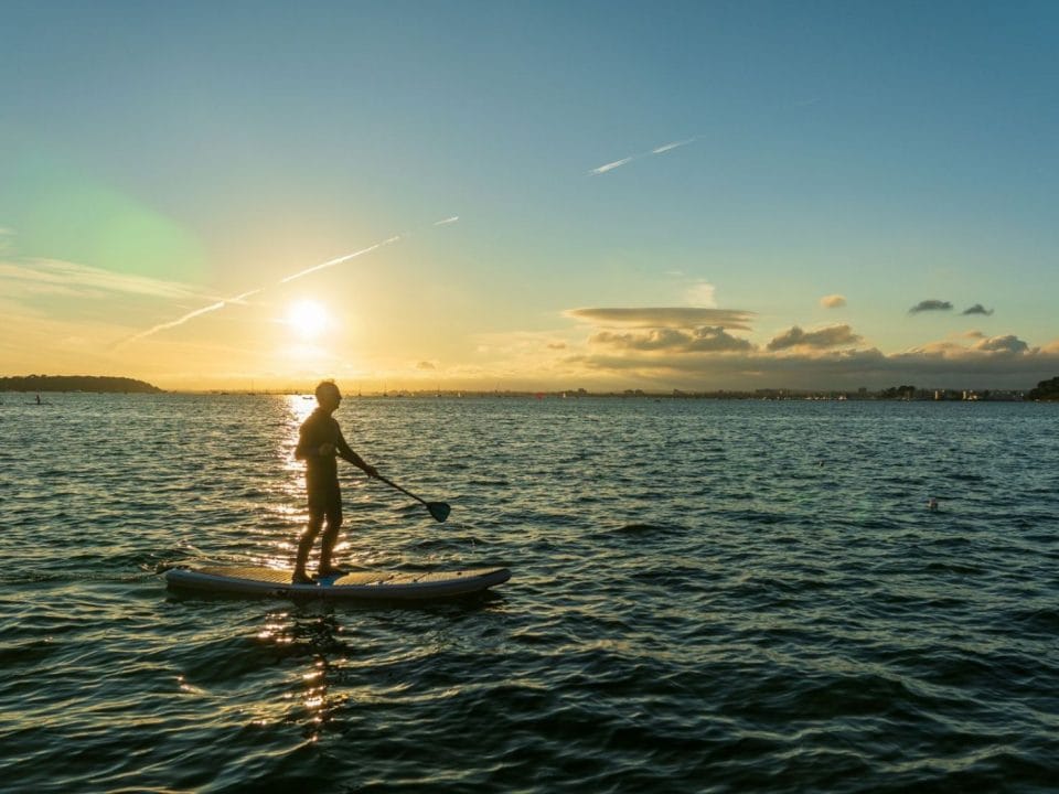 Egy férfi stand-up paddlingozik a tengeren.
