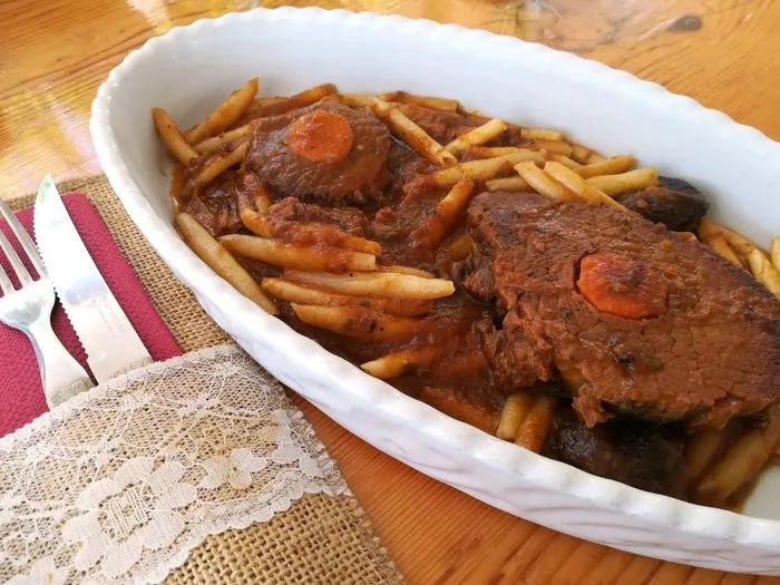 Pašticada dish on a plate with cutlery