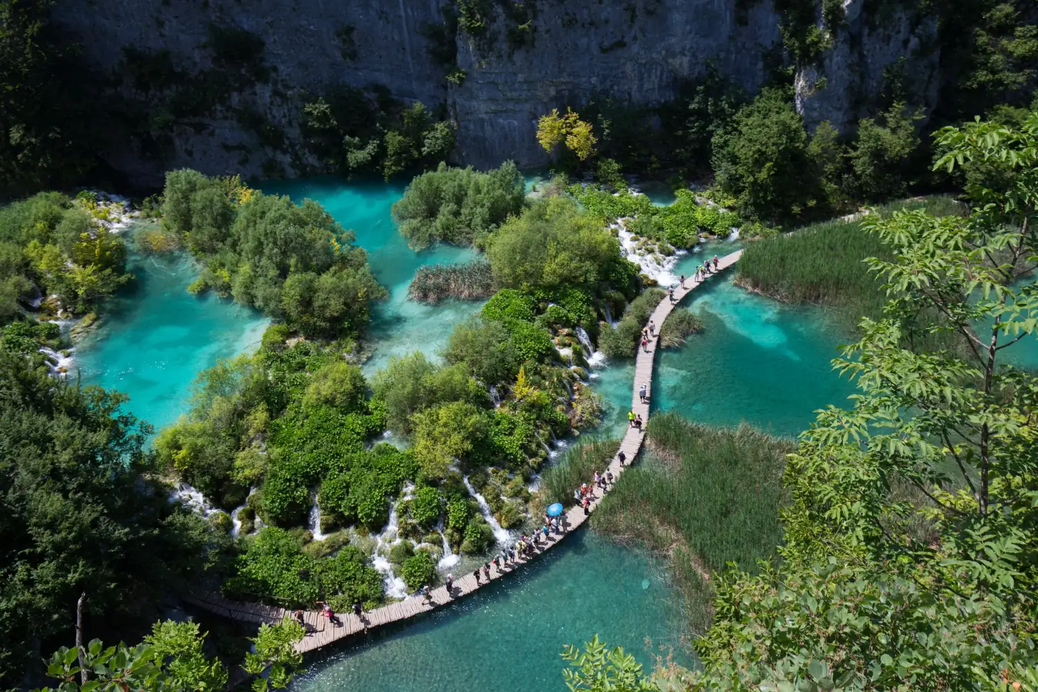 A wooden boardwalk above a turquoise lake at Plitvice Lakes.